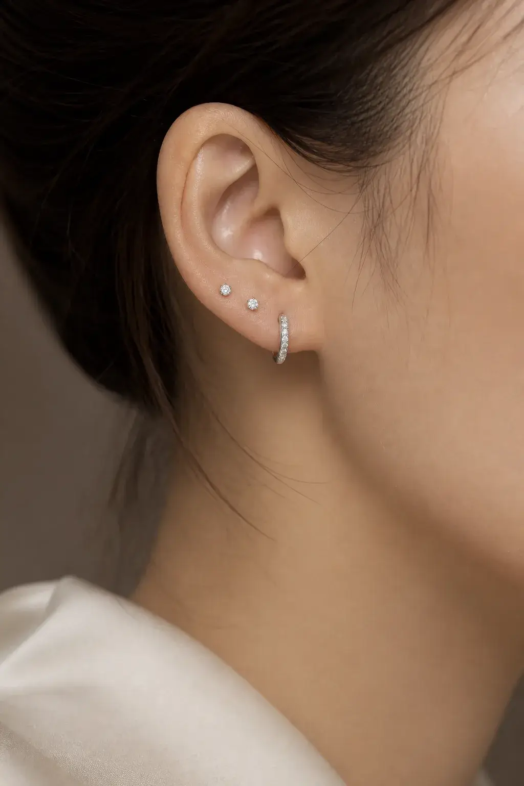 Two small diamond studs and a slim huggie built up on one ear